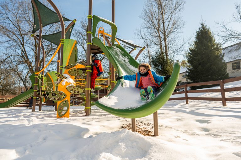 A child goes down a snow-covered slide at the Utica Zoo